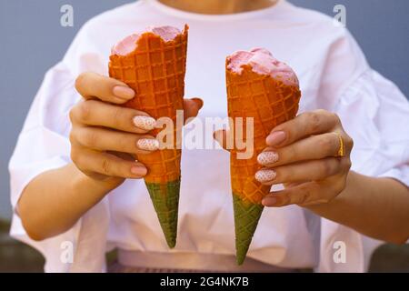 les femmes tiennent main le cône de crème glacée arc-en-ciel. le cône de crème glacée arc-en-ciel - deux mains enholding les cônes de crème glacée dans les couleurs arc-en-ciel à la chaude journée d'été Banque D'Images