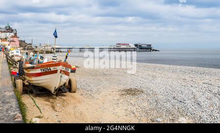 Des tracteurs et des bateaux de pêche bordent la plage de Cromer en face de la jetée. Vu en juin 2021 sur la côte nord de Norfolk. Banque D'Images