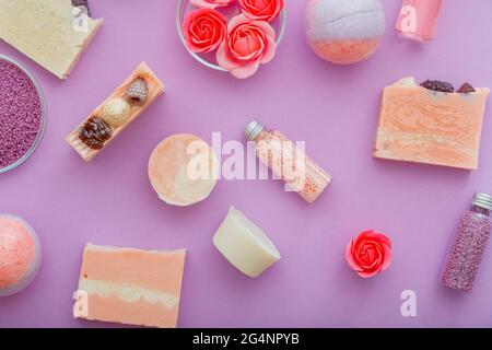 Produits de bain spa à savon rose coloré faits main sur fond violet. Poudre de bain de perles de bombe. Produits de bain pour le soin de la peau spa du corps bien-être Banque D'Images