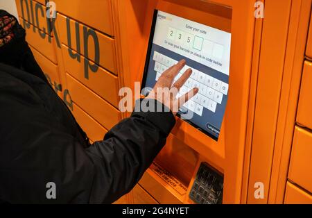 Londres, Royaume-Uni - 04 février 2019 : une femme âgée entre son code dans le kiosque libre-service Orange Amazon (détaillant en ligne), près de chez elle Banque D'Images