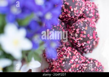 Boîte de chocolats aux noix rouges sur une table en bois ornée de fleurs. Fête des mères ou fête de la Saint-Valentin. Banque D'Images