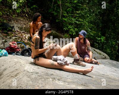 Minca, Magdalena, Colombie - Mai 19 2021: Femme asiatique regardant son téléphone, Brown Latin et Caucasiens hommes parlant les uns les autres, ils reposent sur un grand R Banque D'Images