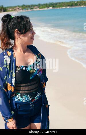 Femme de latina mûre debout sur la plage regardant l'horizon Banque D'Images