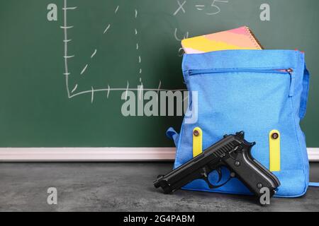 Pistolet et sac à dos sur table en classe. Concept de tir à l'école Banque D'Images