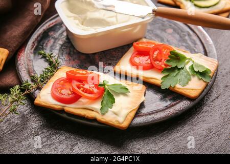 Délicieux craquelins au fromage et aux tomates sur fond sombre Banque D'Images