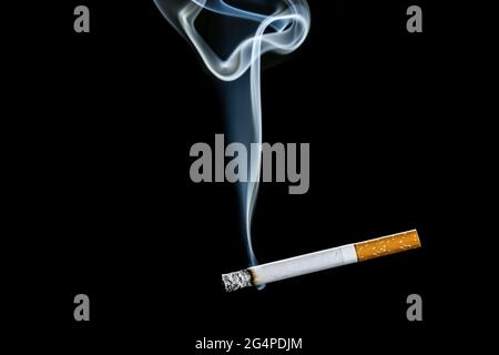 Cigarette allumée sur fond sombre Banque D'Images