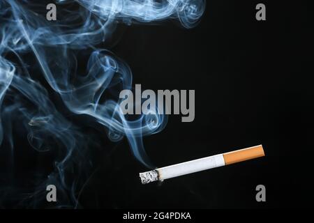 Cigarette allumée sur fond sombre Banque D'Images