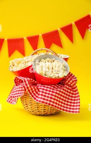 Panier avec pop-corn savoureux sur fond de couleur. Fête de Festa Junina (Festival de juin) Banque D'Images