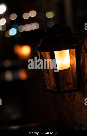 lanterne sombre de streetlight éclairée d'une lumière orange au milieu de la nuit sombre avec un fond de lumières non-focus, bokeh vertical Banque D'Images