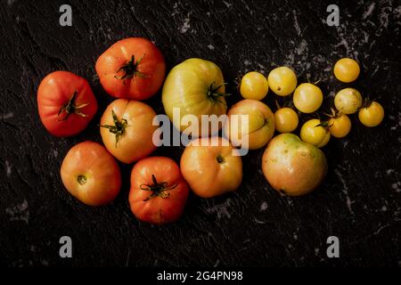 Tomates organiquement maison dans différentes nuances de rouges, d'oranges et de jaunes, y compris les tomates cerises Banque D'Images