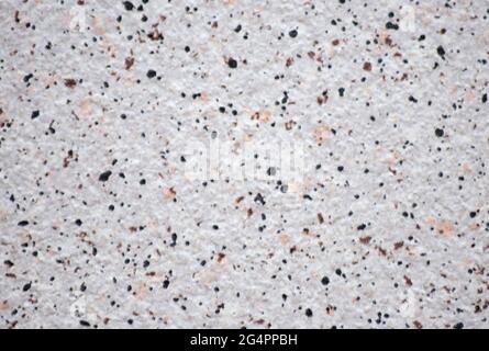 Granit blanc avec petites taches orange et noir, gros plan de la surface en pierre naturelle. Arrière-plan, motif, texture. Banque D'Images