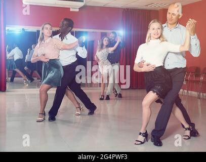 Les couples adultes dansant la salsa dansent ensemble dans un studio moderne Banque D'Images