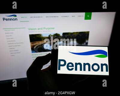Personne tenant un smartphone portant le logo de la société britannique d'approvisionnement en eau Pennon Group plc à l'écran devant le site Web. Mise au point sur l'affichage du téléphone. Banque D'Images