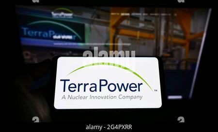 Personne tenant un téléphone portable avec le logo de la société américaine de réacteur nucléaire TerraPower LLC à l'écran devant la page Web des affaires. Mise au point sur l'affichage du téléphone. Banque D'Images