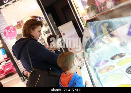 Mère avec des fils qui choisissent de la crème glacée dans le magasin Banque D'Images