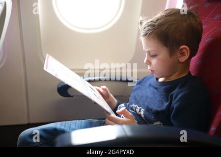 Portrait de l'enfant étudiant les consignes de sécurité à bord de l'avion Banque D'Images