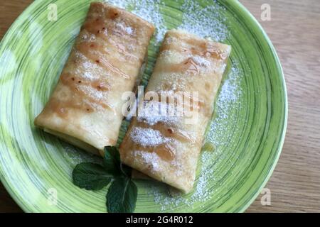 Crêpes farcies sur une assiette verte dans le restaurant Banque D'Images