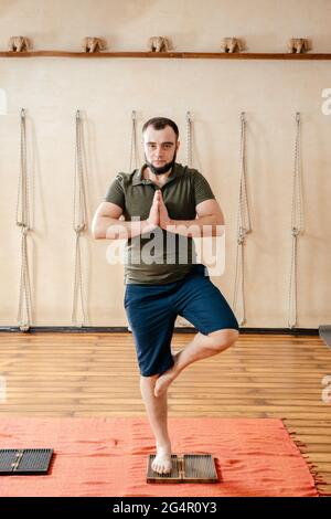 Jeune homme debout sur le tableau de sadhu dans un studio de yoga. Pratique de yoga avec lit de clous. Pied sur le bureau en bois avec des clous métalliques pointus Banque D'Images