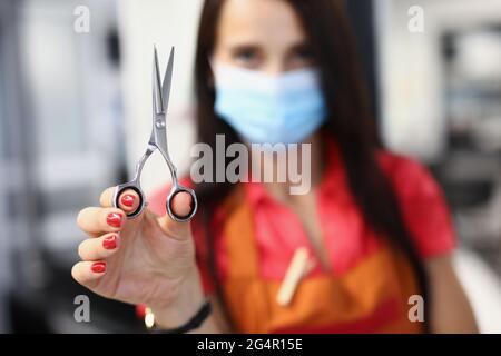 Femme coiffeur dans un masque de protection médicale tient des ciseaux à la main Banque D'Images