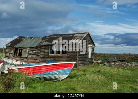 Vieux bateaux de pêche à côté d'un hangar en bois délabré sur la rive à Beadnell, Northumberland, Royaume-Uni Banque D'Images