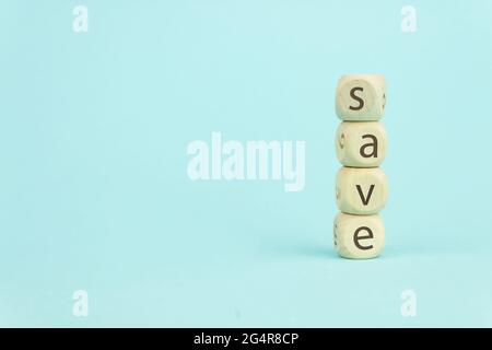 Quatre cubes de jouets en bois disposés verticalement sur fond bleu avec texte SAVE, business groenth et Save concept Banque D'Images