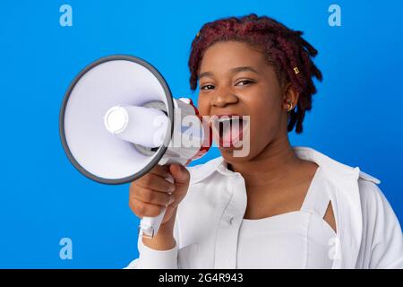 Femme afro-américaine utilisant le mégaphone sur fond bleu Banque D'Images