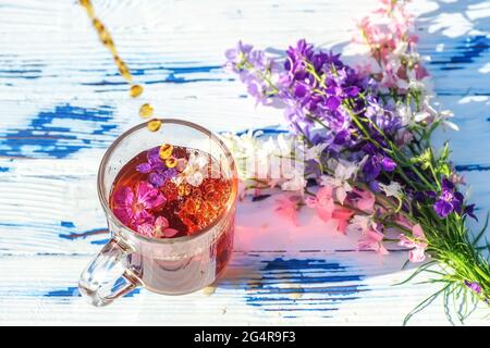Tasse de thé en verre avec fleurs sauvages et bouquet sur une table en bois en gros plan Banque D'Images