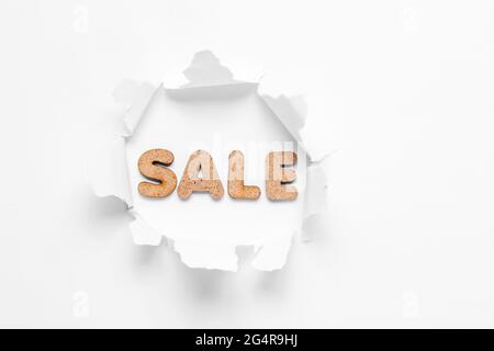 Vente de mot dans trou déchiré sur fond blanc. Concept d'achat minimal Banque D'Images