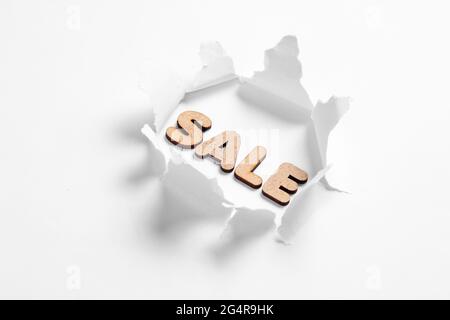 Vente de mot dans trou déchiré sur fond blanc. Concept d'achat minimal Banque D'Images