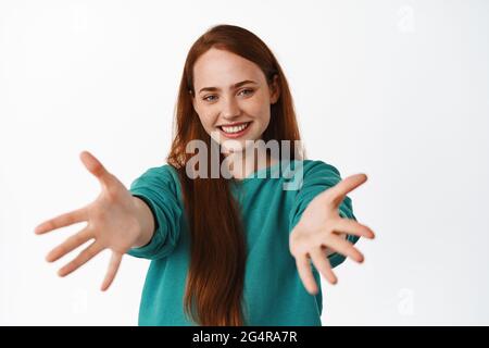 Image de fille de gingembre étire les mains et sourire, recevoir quelque chose, veut tenir ou embrasser, vous embrassant, se tenant amical contre fond blanc Banque D'Images