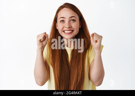 Image d'une jeune fille pleine d'espoir regardant l'écran avec des poings serrés et un visage souriant excité, se criant pour l'équipe, applaudissant et célébrant la victoire, regardant Banque D'Images