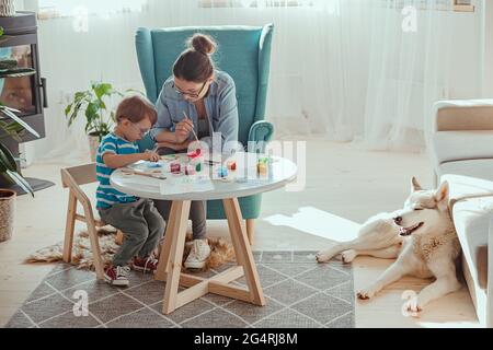 Maman et enfant peignent ensemble à la maison avec le chien Banque D'Images