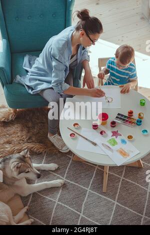 Maman et enfant peignent ensemble à la maison avec le chien Banque D'Images