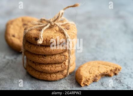 Délicieux biscuits aux pépites de chocolat noués avec une corde sur fond bleu flou Banque D'Images