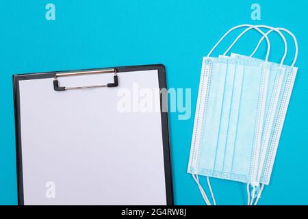 Presse-papiers noir avec feuille de papier blanche vierge couchée sur une table bleue - vue du dessus, couché à plat Banque D'Images