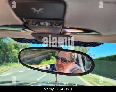 Vue arrière du conducteur mâle regardant le rétroviseur intérieur de la voiture Banque D'Images