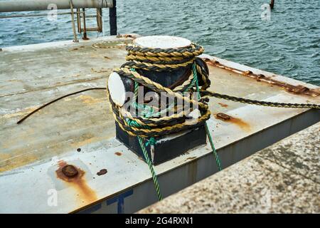 Vue latérale d'un bollard à croûtes avec corde d'amarrage pour fixer un bateau Banque D'Images