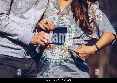 Jeune couple enceinte marquant le jour de naissance de l'enfant dans le calendrier. Concept d'attente de bébé. Planification de l'avenir. Homme adulte et femme enceinte manifestant de l'échelle Banque D'Images