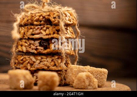 Biscuits faits maison avec graines de tournesol et raisins secs attachés avec ficelle et morceaux de sucre de canne brun sur une table en bois. Gros plan mise au point sélective Banque D'Images