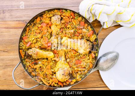 Vue aérienne d'un riz au poulet et au safran ou à la paella de poulet dans le moule à paella classique et une louche à servir sur la plaque blanche. Espagnol typique FO Banque D'Images