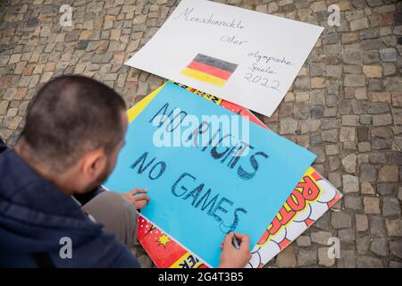 Berlin, Allemagne. 23 juin 2021. Un homme écrit "pas de droits, pas de jeux" sur un panneau à la porte de Brandebourg lors d'une protestation de plusieurs organisations de droits de l'homme contre l'attribution des Jeux Olympiques d'hiver de 2022 à Pékin. Credit: Christoph Soeder/dpa/Alay Live News Banque D'Images