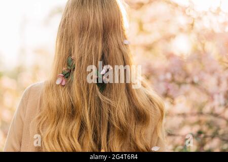 Jolie jeune femme, dans une délicate robe vintage, debout à côté des fleurs roses colorées des arbres, des femmes romantiques Banque D'Images