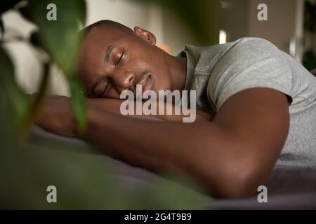 Jeune Africain dormant dans son lit à la maison Banque D'Images