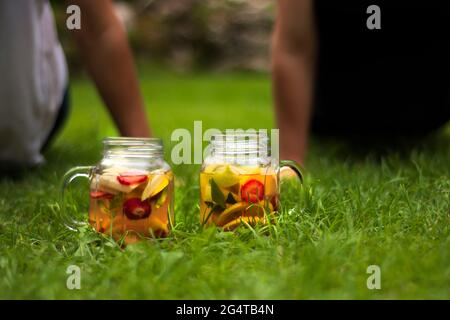 Deux jarres de verre, délicieux détox avec des fruits rouges, orange et jaunes, debout sur l'herbe. Lunettes Selective Focus. Banque D'Images
