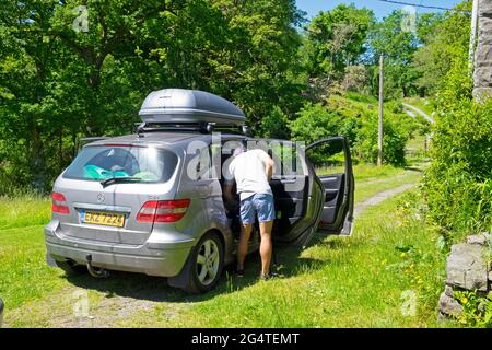 Le père emballant la voiture se prépare à partir de vacances staycation après Covid 19 grippe pandémique a 2021 au pays de Galles au Royaume-Uni KATHY DEWITT Banque D'Images