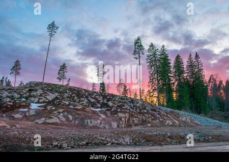 Magnifique coucher de soleil orange rouge dans le ciel au-dessus des falaises de montagnes et de grands pins, nuages pittoresques illuminés par le soleil Banque D'Images