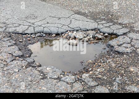 Grand trou de pot rempli de pluie problème de rue endommagé par l'eau Banque D'Images