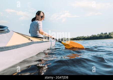 Une jeune femme flotte sur la rivière dans un bateau. Banque D'Images