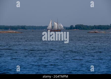 Helsinki / Finlande - 22 JUIN 2021 : une vieille goélette en bois à deux mâts naviguant à travers l'horizon entre deux skerries. Banque D'Images