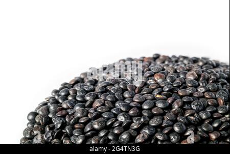 Pile de lentilles de béluga, gros plan. De nombreuses petites lentilles organiques noires. Légume à saveur terreuse, texture ferme et riche en protéines. Utilisé comme accompagnement, en sou Banque D'Images